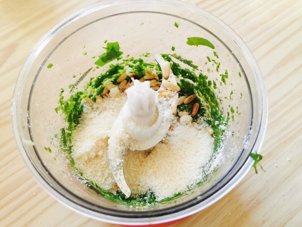 grated parmigiano and toasted pine nuts in food processor with rocket pesto