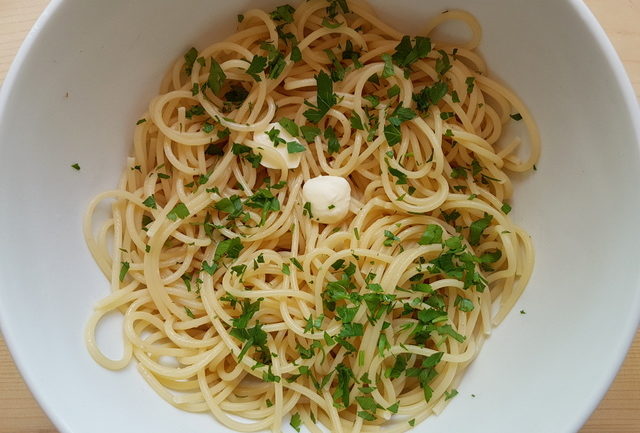 cooked vermicelli with butter and parsley in white bowl