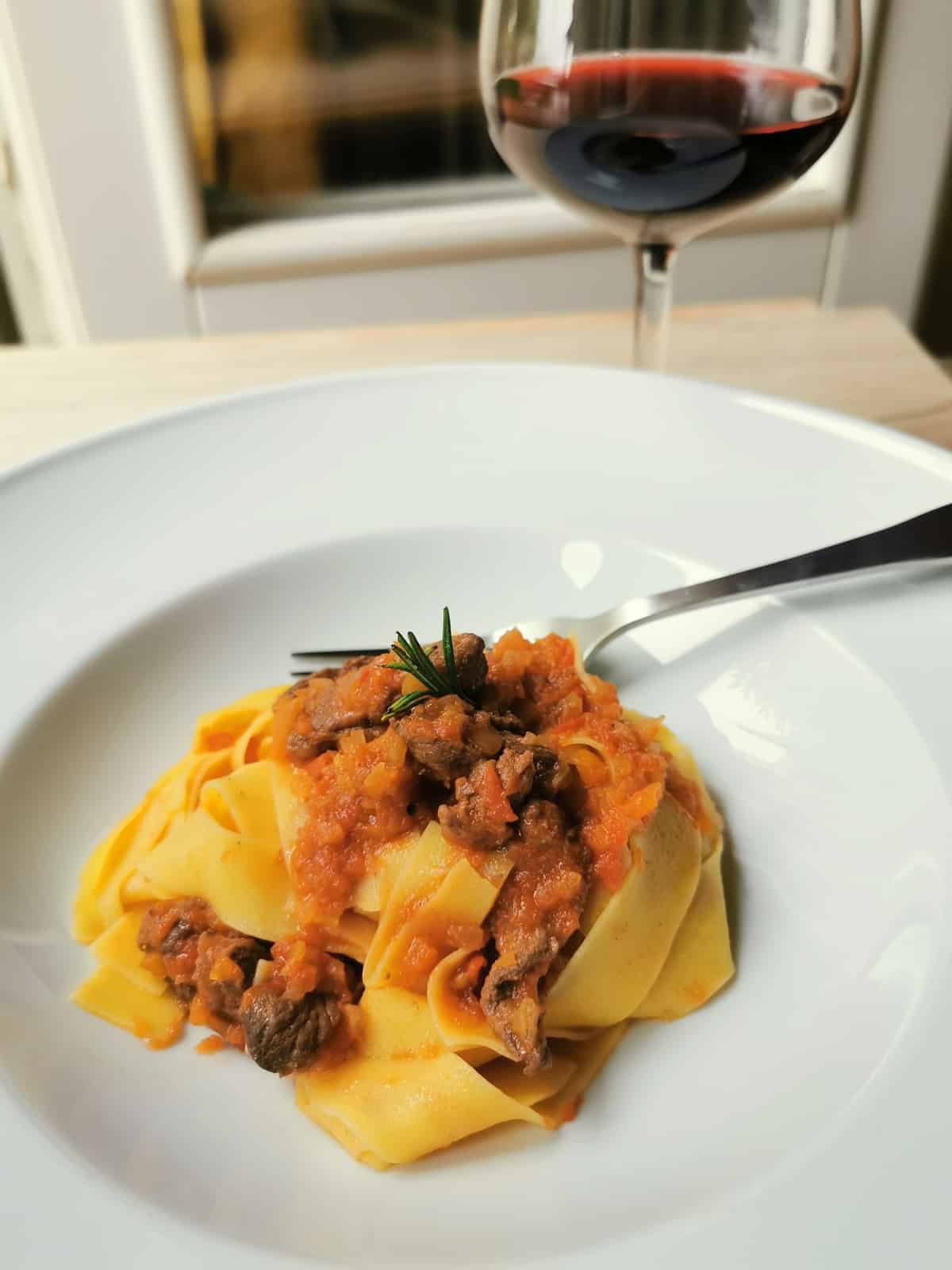 wild boar ragu with pappardelle in white bowl.