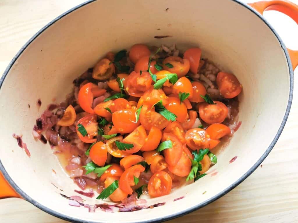 chopped tomatoes and parsley in Dutch oven with onions and lardo