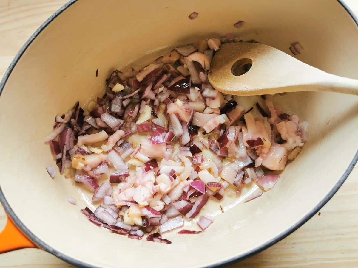 chopped red onion and chopped lardo cooking in Dutch oven